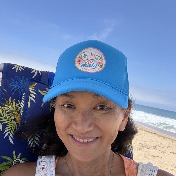 A member of Au Mahj Group wearing the logo trucker hat at the beach