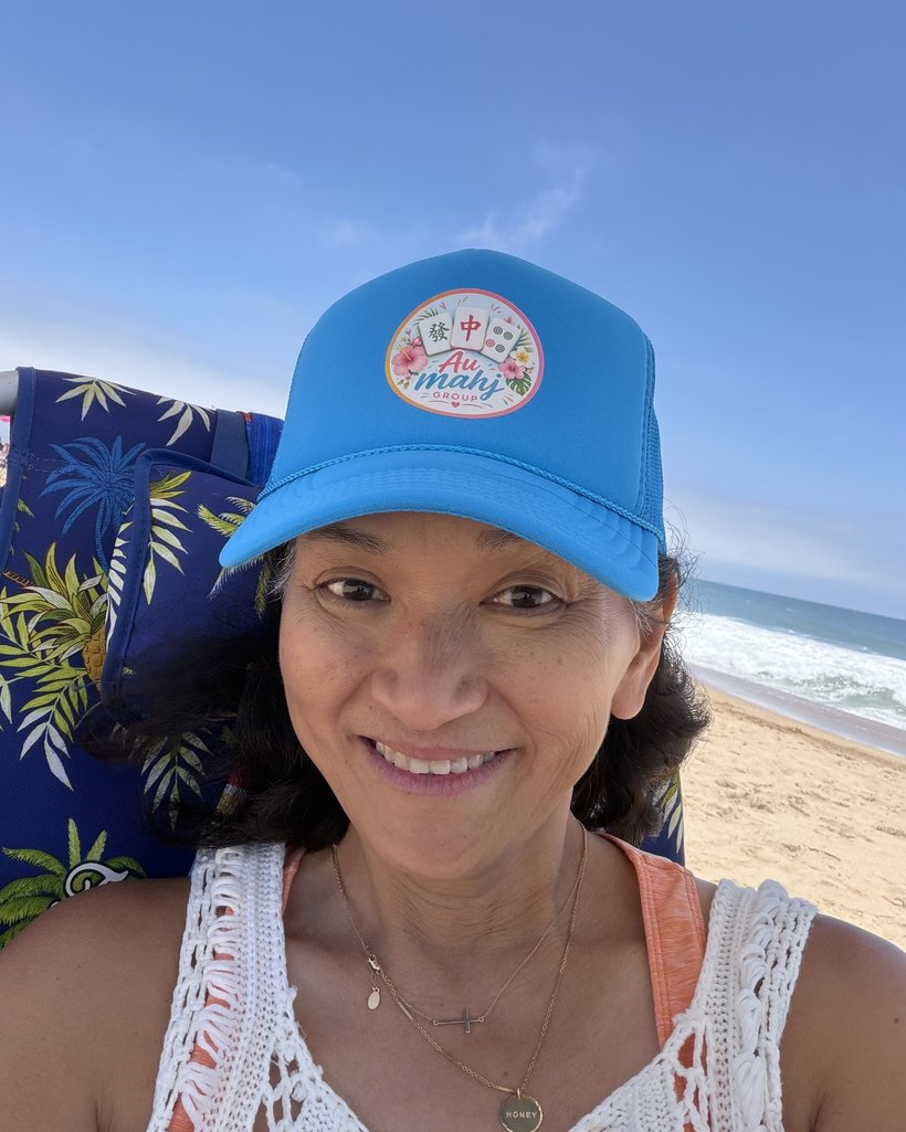 Nguyet, founder of Au Mahj Group, at the beach wearing the logo trucker hat