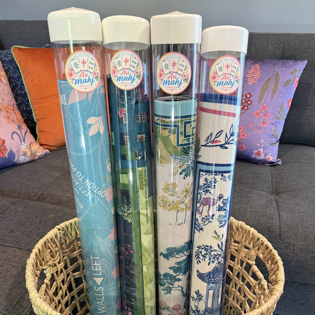 Four clear Au Mahj Group mat storage tubes holding rolled mahjong mats, standing in a woven basket